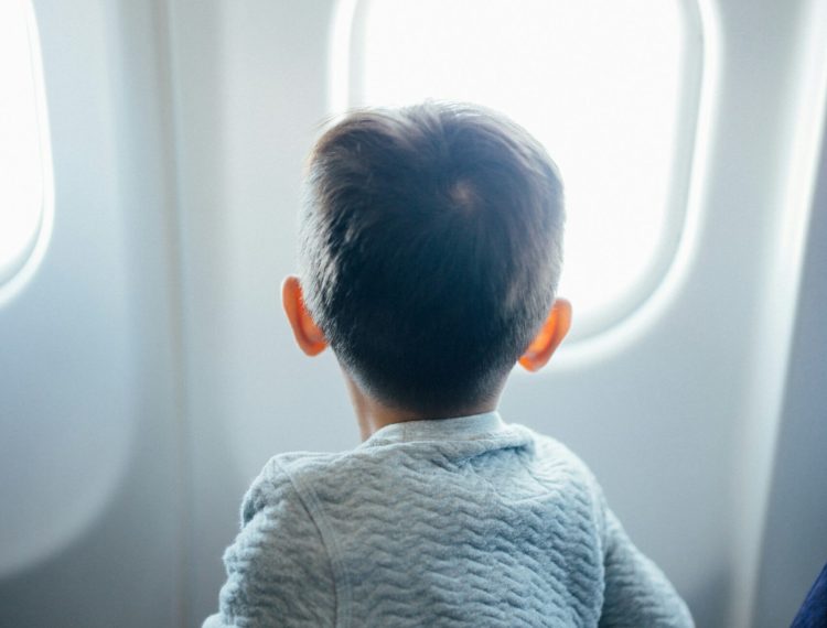 boy airplane window family travel tips