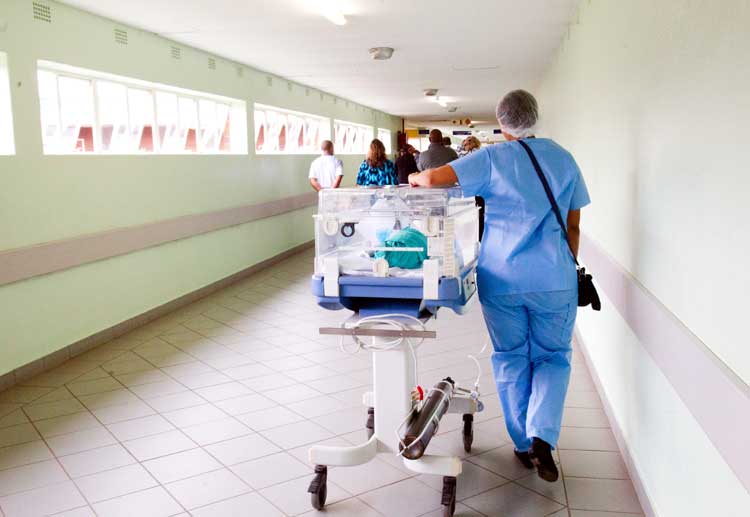 nicu baby in incubator being wheeled down hospital hall