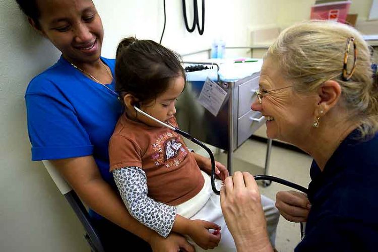 mother holds daughter during doctor visit growth chart