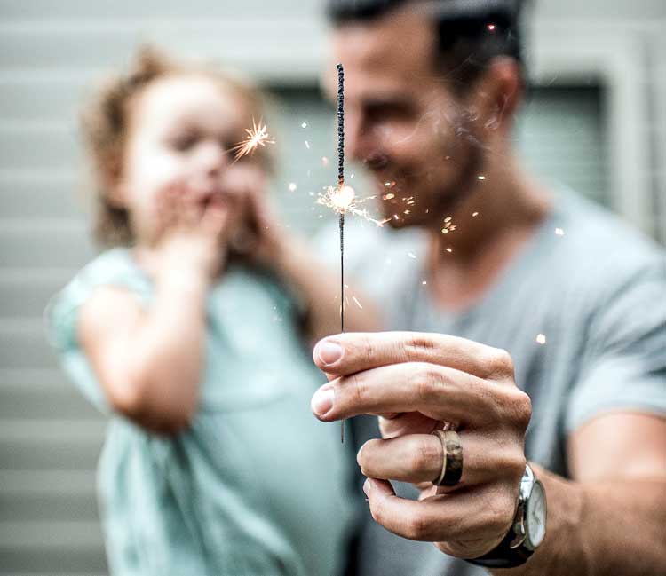 dad holds child and sparkler